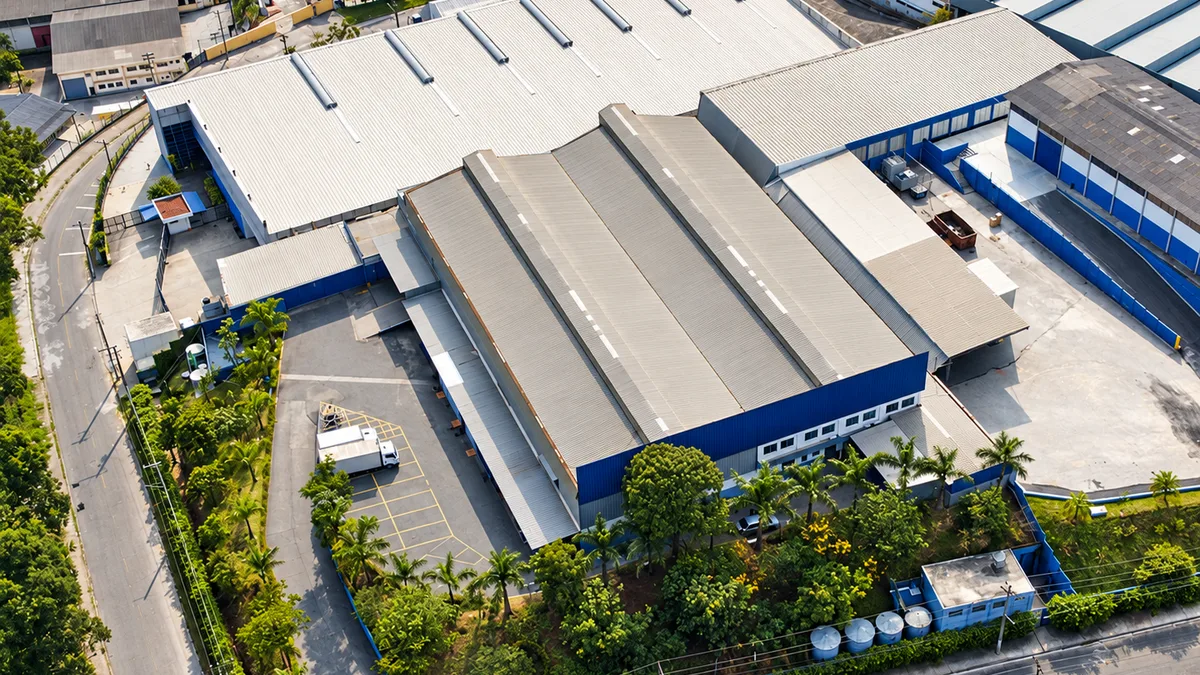 Vista aérea da fábrica da Wolfer em Caieiras: galpões extensos cercados de mata.